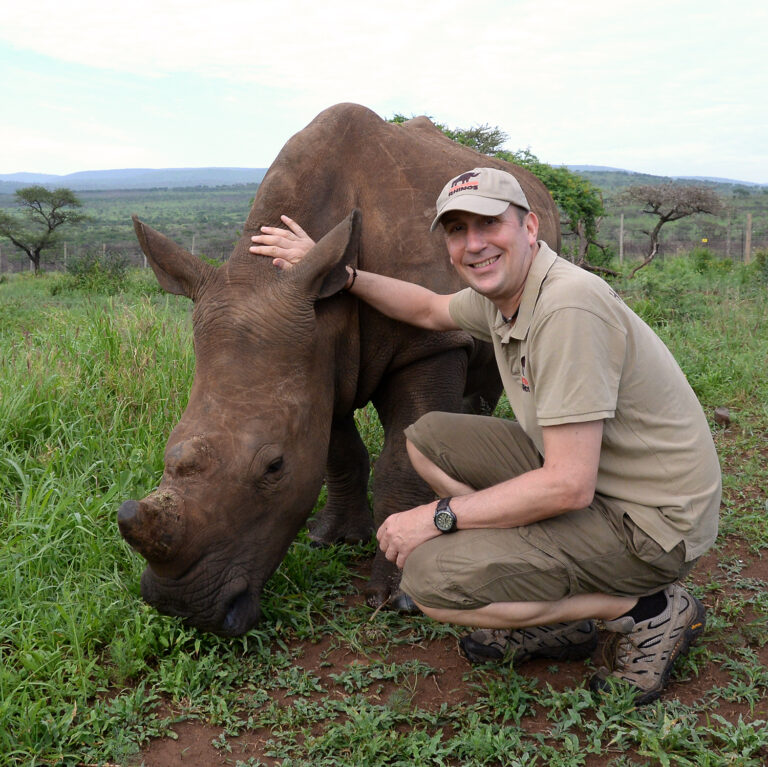 Simon Jones kneeling next to a rhino calf